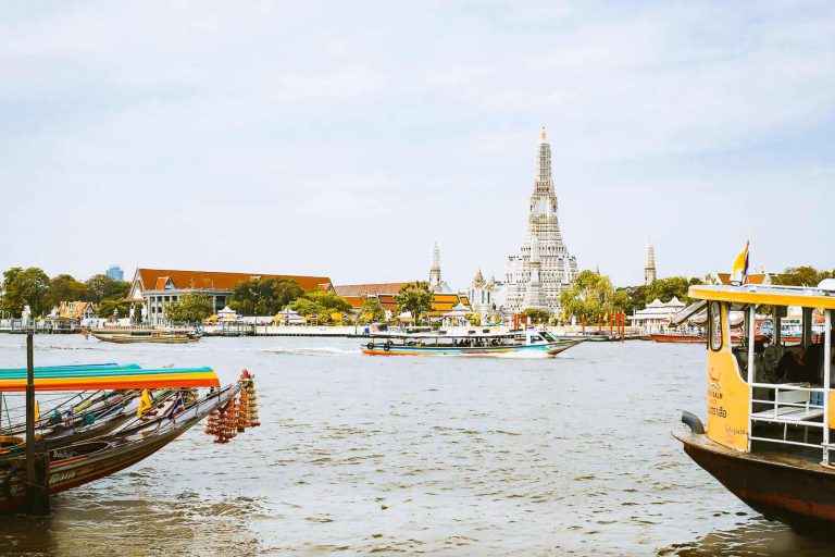 View Of Wat Arun, Temple Of Dawn, From Across The River With Local Boat Passin