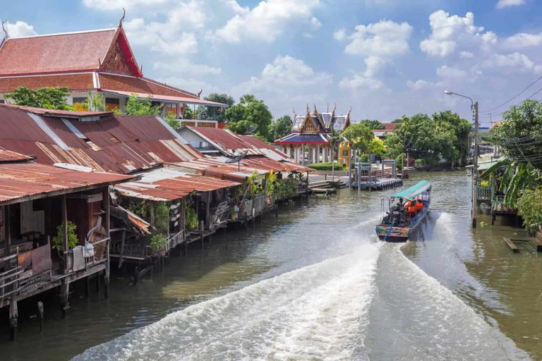 A Longtail Boat In The Bangkok Canal With Temples Around